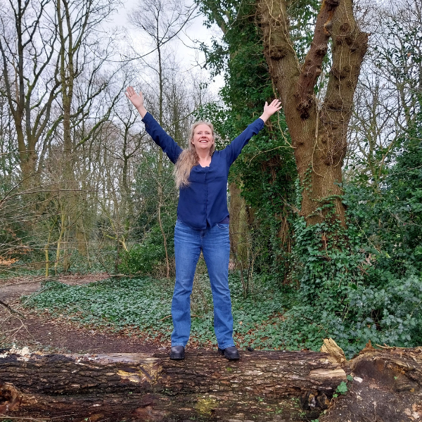 Pauline de Vries op een omgevallen boom in het bos